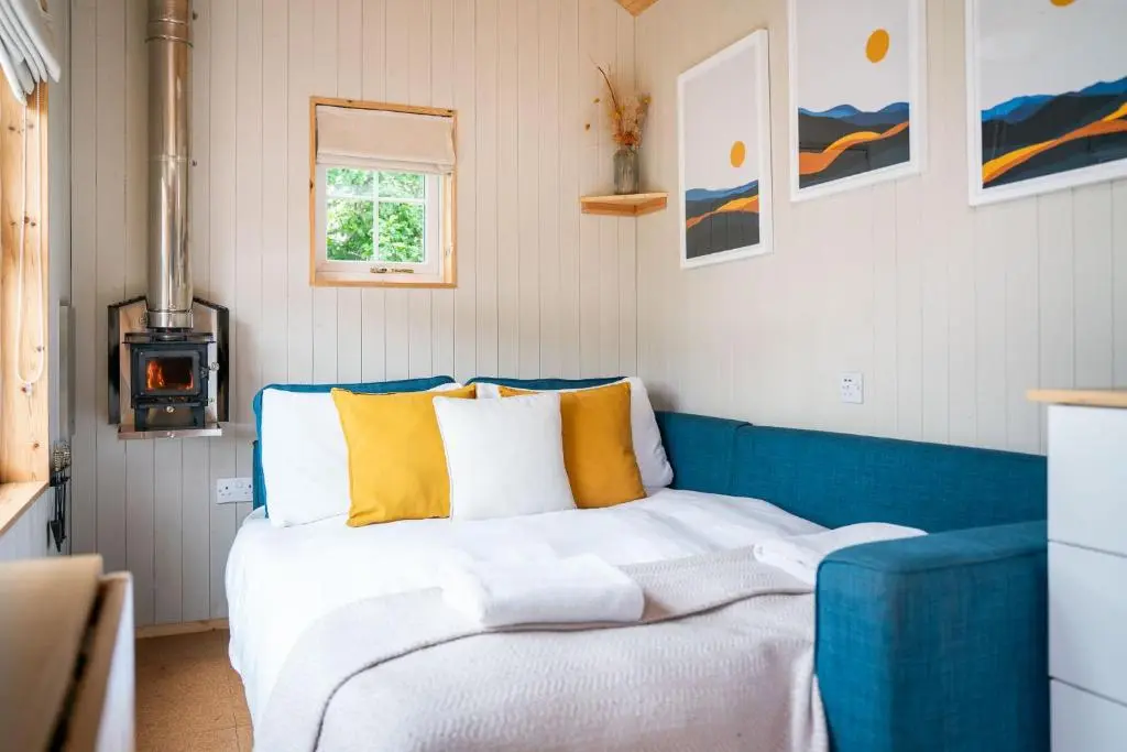 a bed in a room with a blue couch at Ailsa- Enchanting Tiny House with wood burner and hot tub in Cairngorms in Ballater