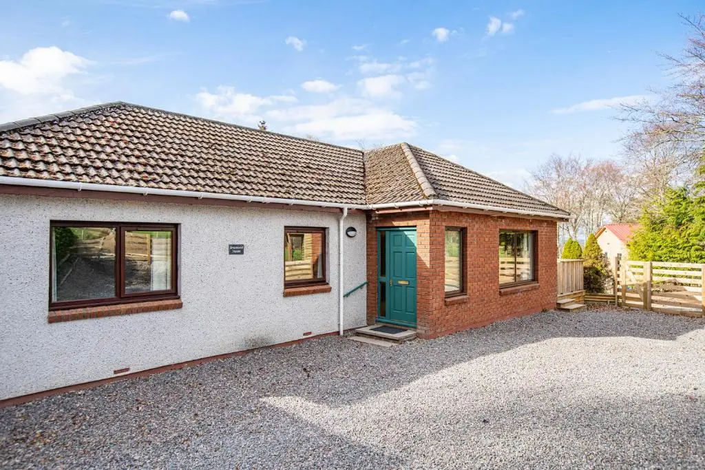 a house with a green door in a driveway at Breckland House with Hot Tub in Belladrum