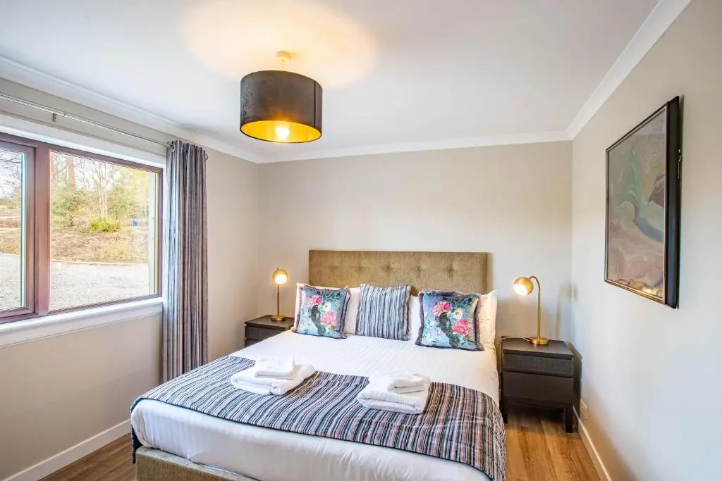 a bedroom with a bed and a window at Breckland House with Hot Tub in Belladrum