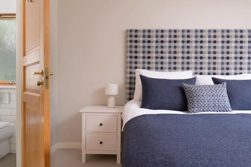 a bedroom with a bed with blue and white pillows at Ballater Bungalow - 4 bed - Beautiful Garden in Ballater
