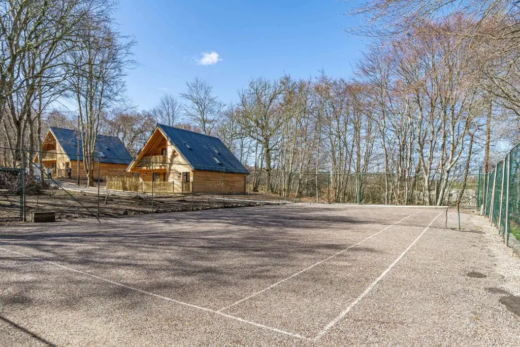 a tennis court in front of a house at Gorse Lodge 9 with Hot Tub in Belladrum