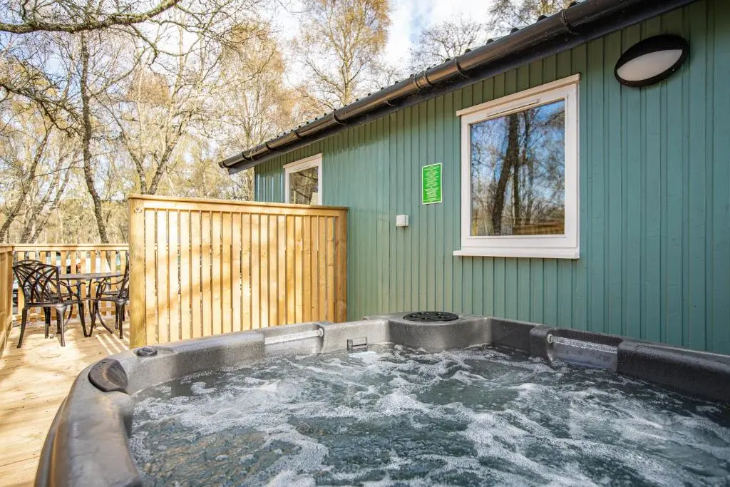 a hot tub in a yard next to a green house at Gorse Lodge 9 with Hot Tub in Belladrum