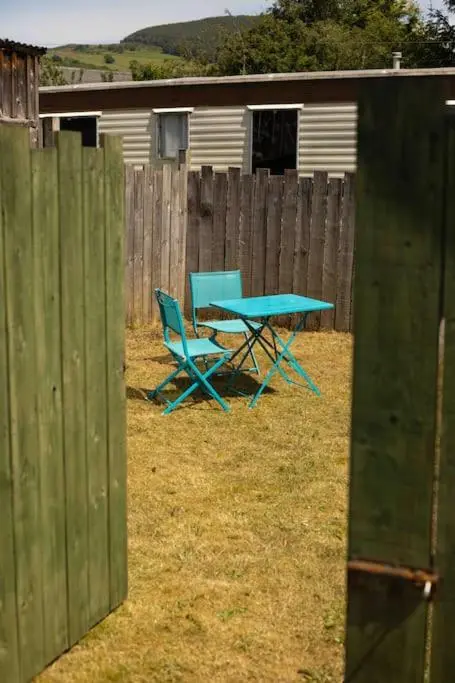 a picnic table and two chairs in front of a fence at Loch Ness village cottage for 2 with free parking & pets welcome in Drumnadrochit