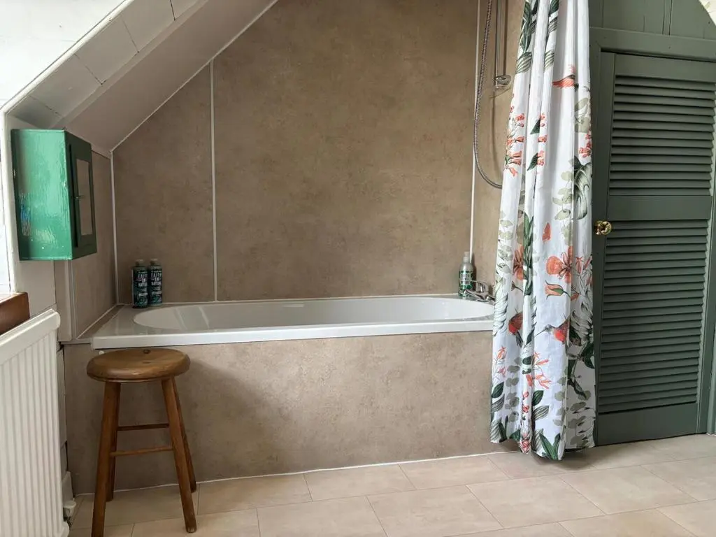 a bathroom with a bath tub and a stool at Loch Ness village cottage for 2 with free parking & pets welcome in Drumnadrochit