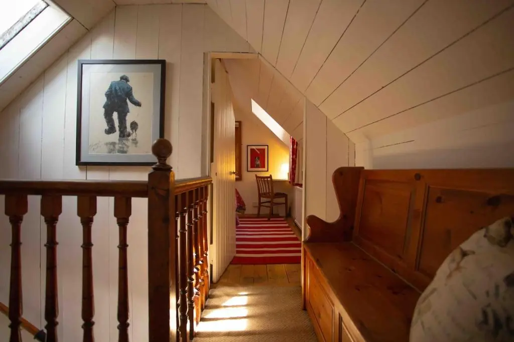 a hallway with a staircase with a picture of a man with a soccer ball at Loch Ness village cottage for 2 with free parking & pets welcome in Drumnadrochit