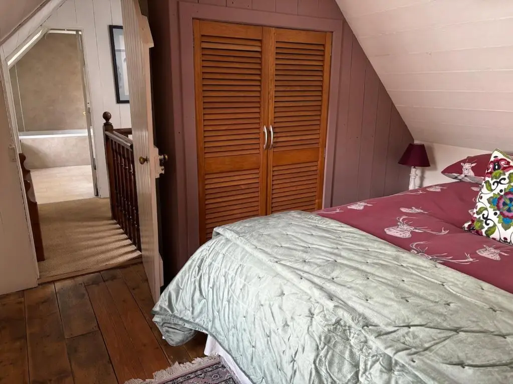 a bedroom with a bed and a wooden closet at Loch Ness village cottage for 2 with free parking & pets welcome in Drumnadrochit