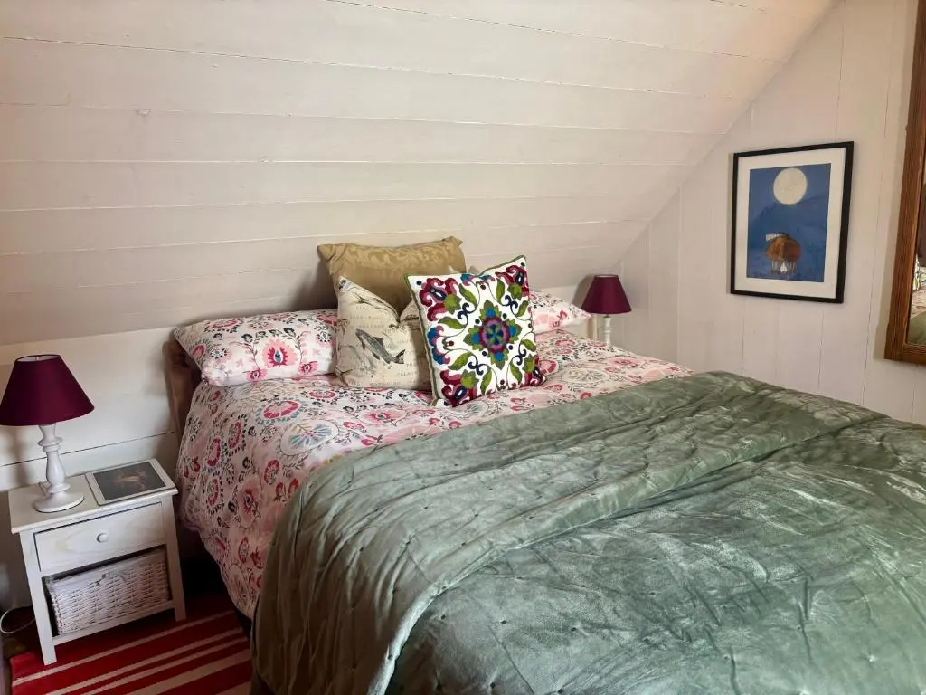 a bedroom with a bed and pillows on it at Loch Ness village cottage for 2 with free parking & pets welcome in Drumnadrochit