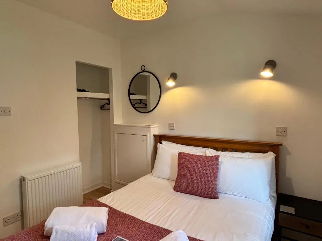 a bedroom with a bed with white sheets and a mirror at Heather Lodge 3 with Hot Tub in Belladrum