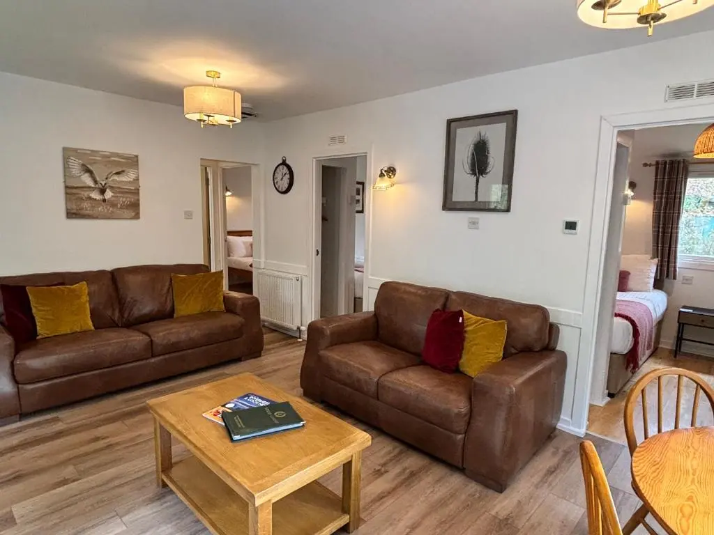 a living room with two couches and a table at Heather Lodge 3 with Hot Tub in Belladrum