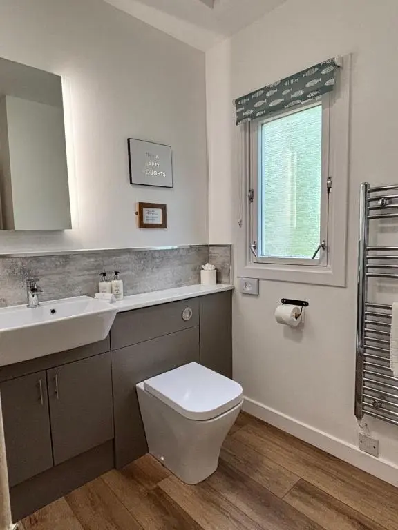 a bathroom with a toilet and a sink and a window at Heather Lodge 3 with Hot Tub in Belladrum