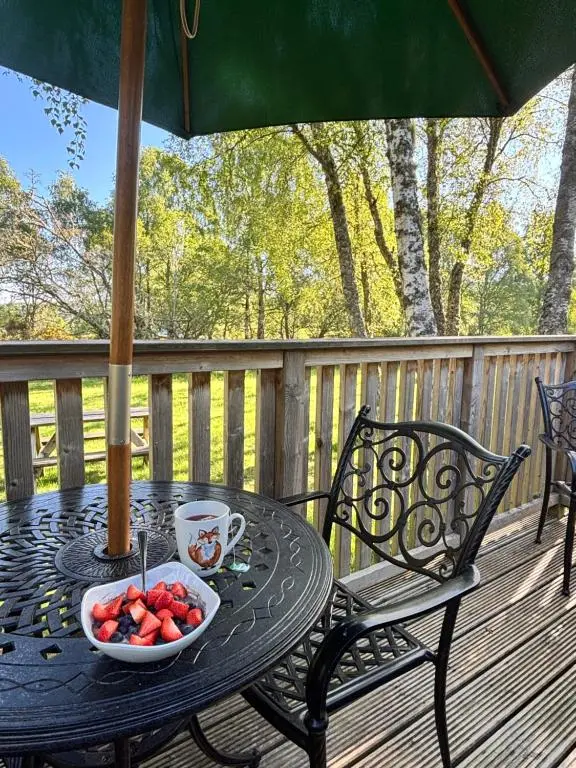 a table with a bowl of fruit on a deck at Heather Lodge 10 with Hot Tub in Belladrum