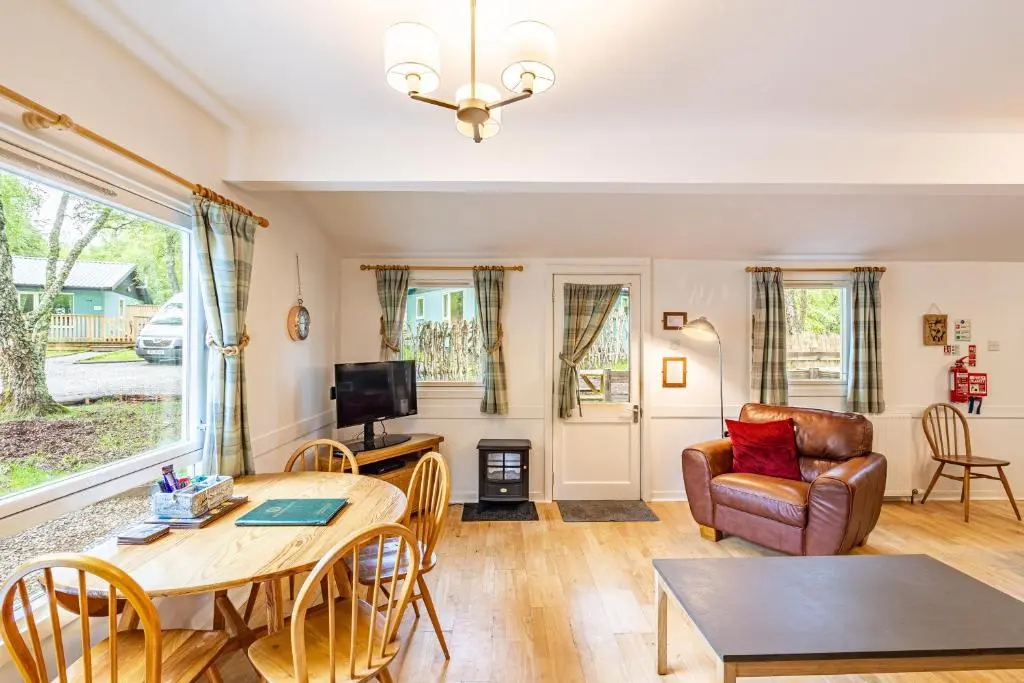 a living room with a table and a couch at Heather Lodge 10 with Hot Tub in Belladrum