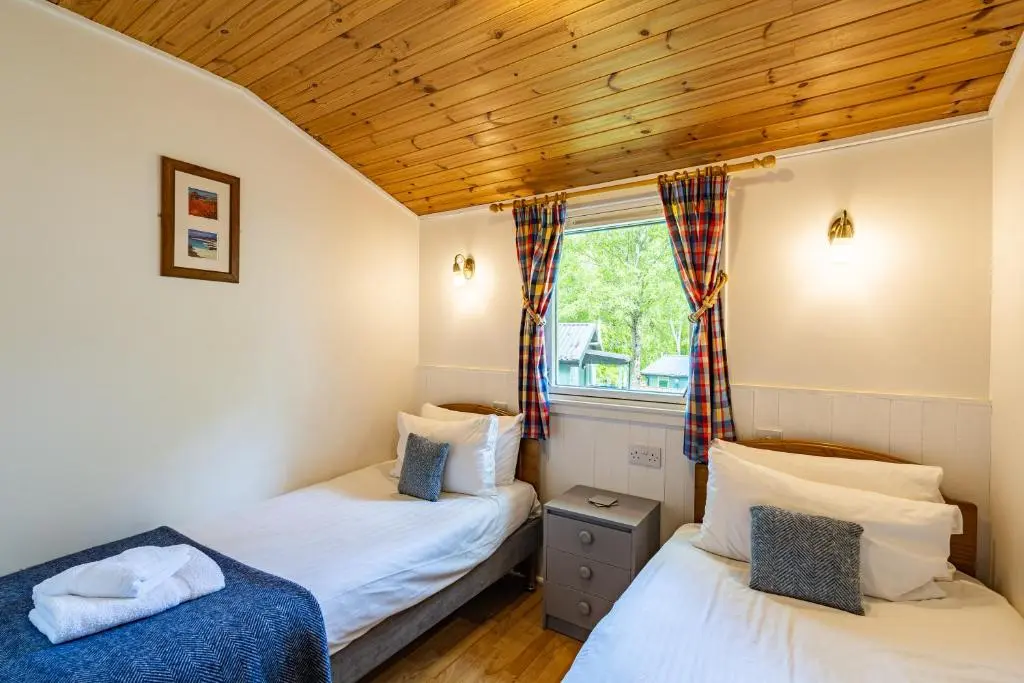 a bedroom with two beds and a window at Heather Lodge 10 with Hot Tub in Belladrum