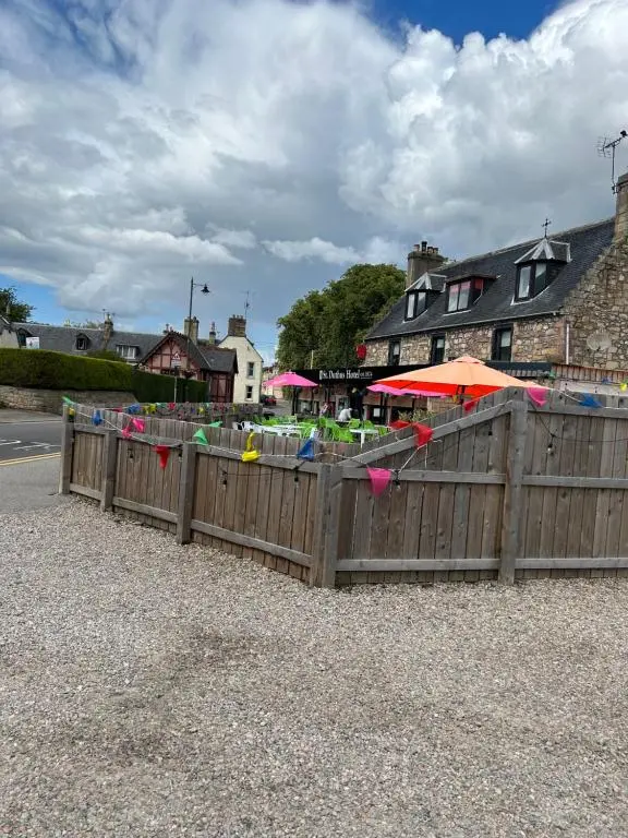 a wooden fence with tables and umbrellas on a street at Saint Blue Apartment in Tain