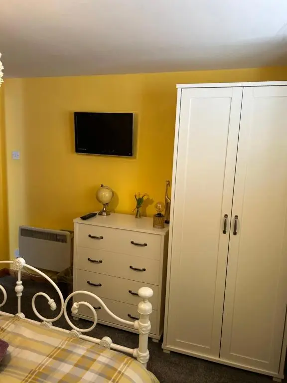 a bedroom with a bed and a tv on a yellow wall at Saint Blue Apartment in Tain
