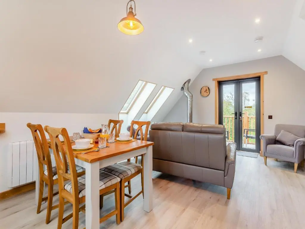 a dining room with a table and chairs and a couch at Tigh-Na-Sgoile in Belladrum