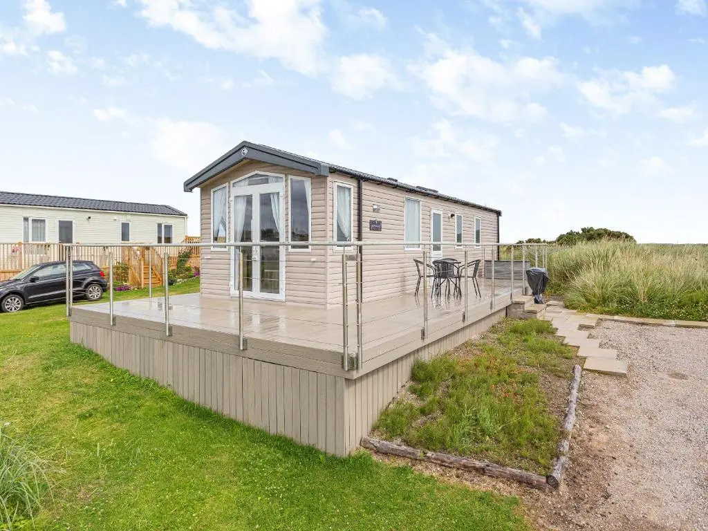 a mobile home with a deck in a yard at The Bordeux in Dornoch
