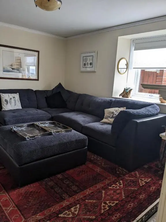 a living room with a blue couch and a rug at Craigmile Cottage in Fraserburgh