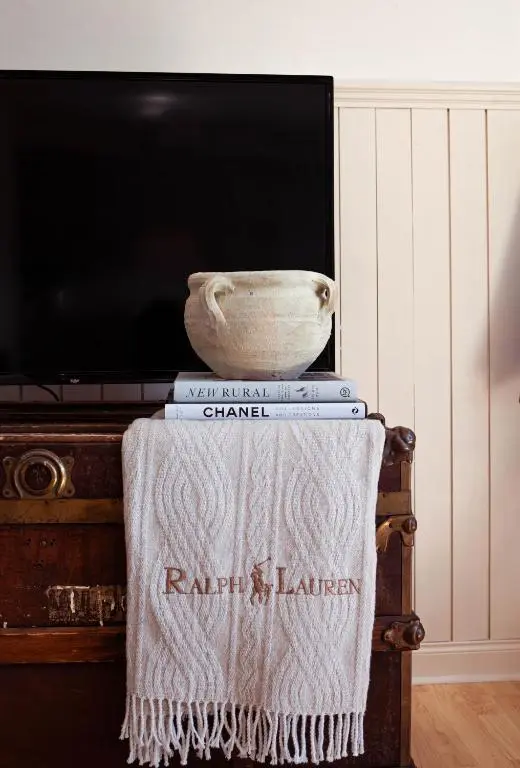 a table with books and a vase on top of a tv at The River Nest in Dalneigh
