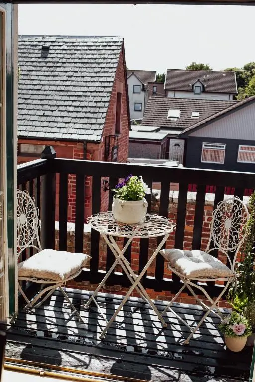 a table and chairs on a balcony with a pot of flowers at The River Nest in Dalneigh