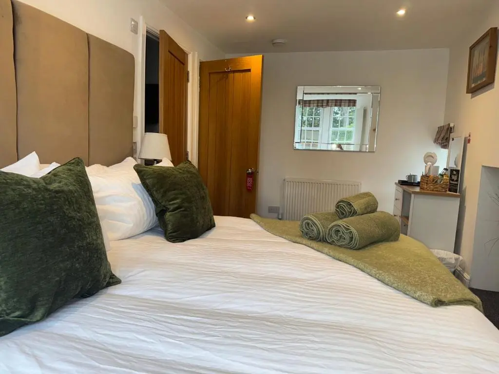 a large white bed with green pillows on it at Altonhill Cottage - room only in Nairn