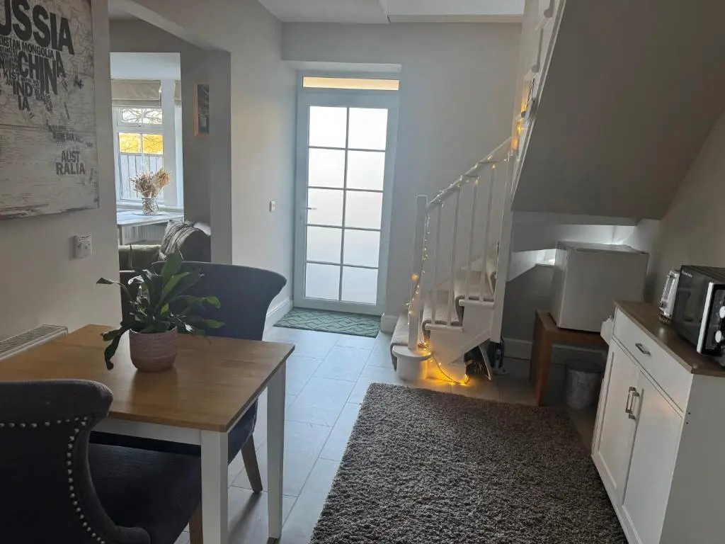 a living room with a table and a staircase at Altonhill Cottage - room only in Nairn
