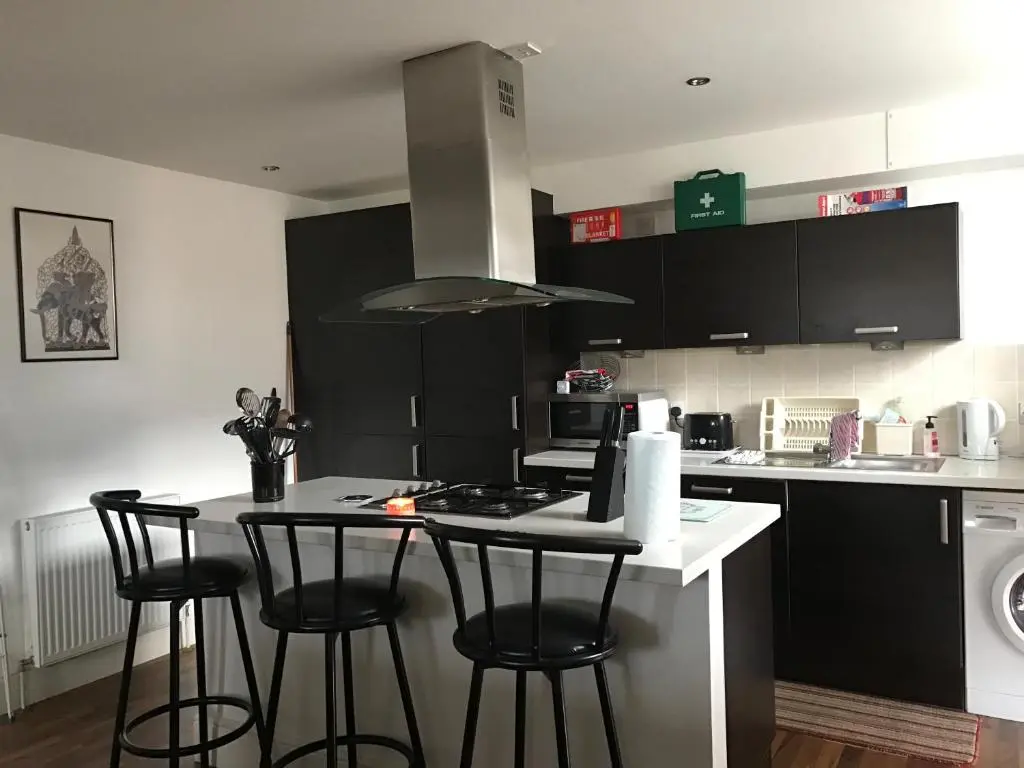 a kitchen with black cabinets and a kitchen island with bar stools at Scardroy Homes Inverness - Central 2 Bedroom with Parking WiFi Smart TVs Sleeps up to 6 in Inverness