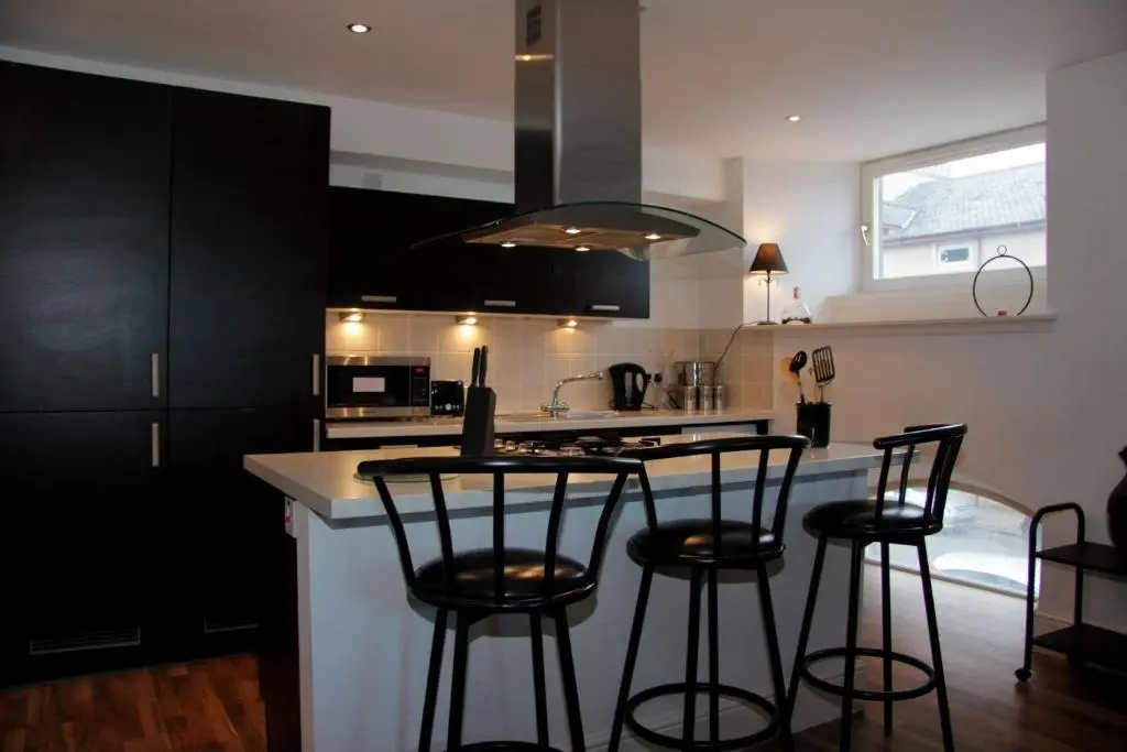 a kitchen with black cabinets and a counter with bar stools at Scardroy Homes Inverness - Central 2 Bedroom with Parking WiFi Smart TVs Sleeps up to 6 in Inverness
