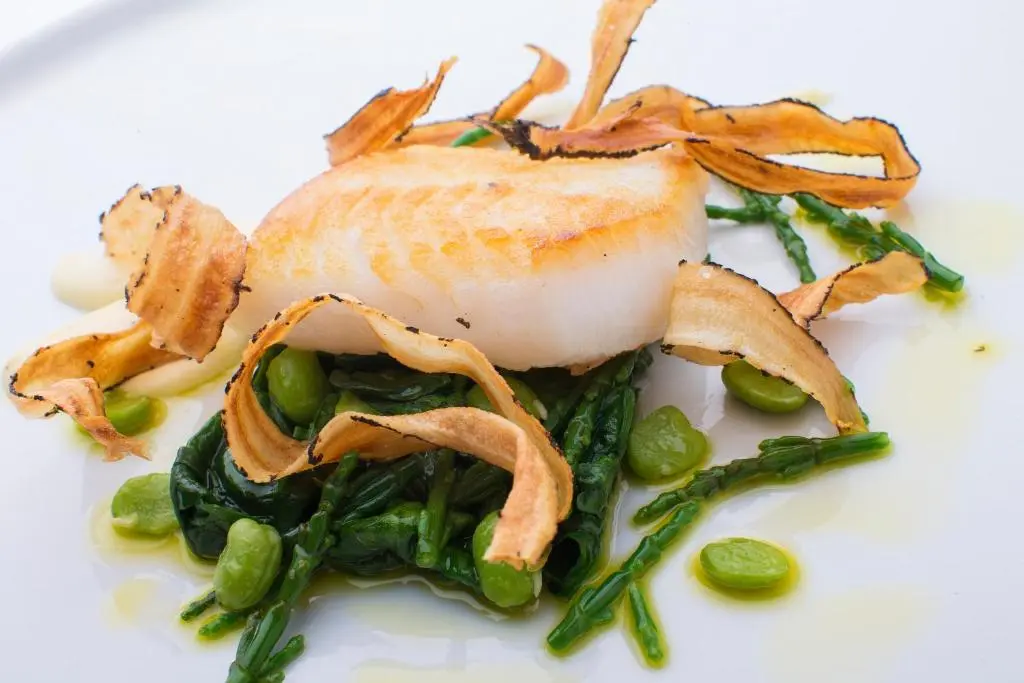 a white plate with a sandwich with greens and chips at The Glenmoriston Townhouse Hotel in Inverness