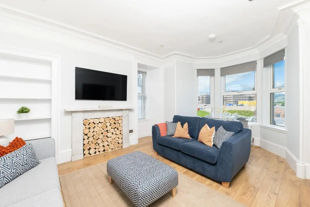 a living room with a blue couch and a fireplace at The Glenmoriston Townhouse Hotel in Inverness