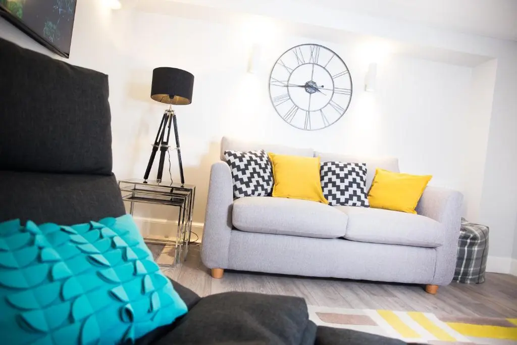 a living room with a couch and a clock on the wall at The Glenmoriston Townhouse Hotel in Inverness