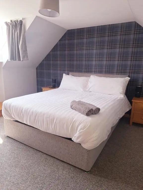 a bedroom with a large bed with a towel on it at 3 Bedroom Townhouse on NC500, Wick, Highland in Wick