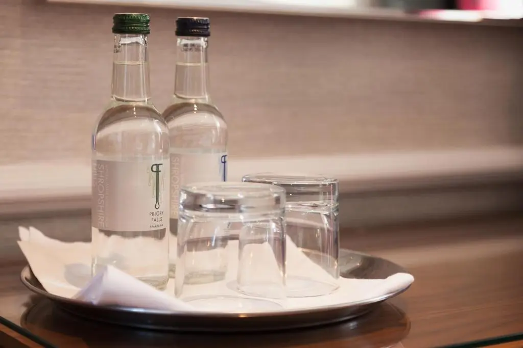 two bottles and glasses on a plate on a table at Craigmonie Hotel Inverness by Compass Hospitality in Inverness