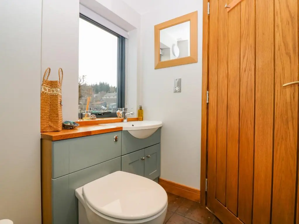 a bathroom with a toilet and a sink and a window at Otakaro in Tomintoul