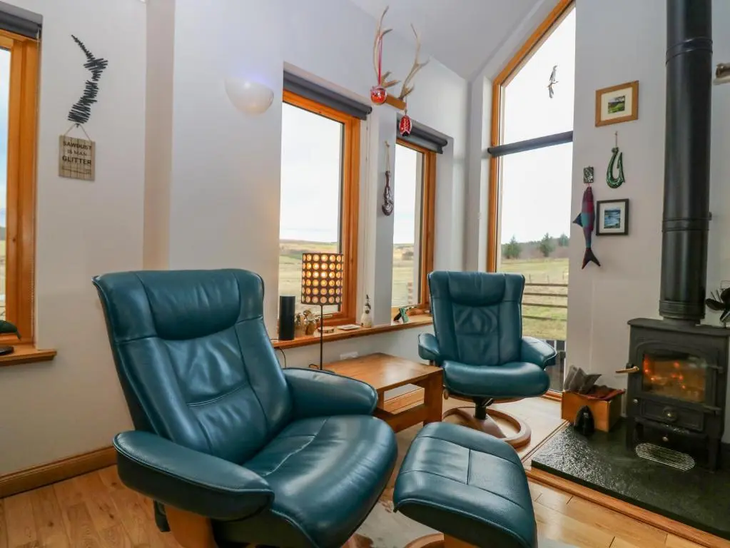 a living room with two chairs and a stove at Otakaro in Tomintoul