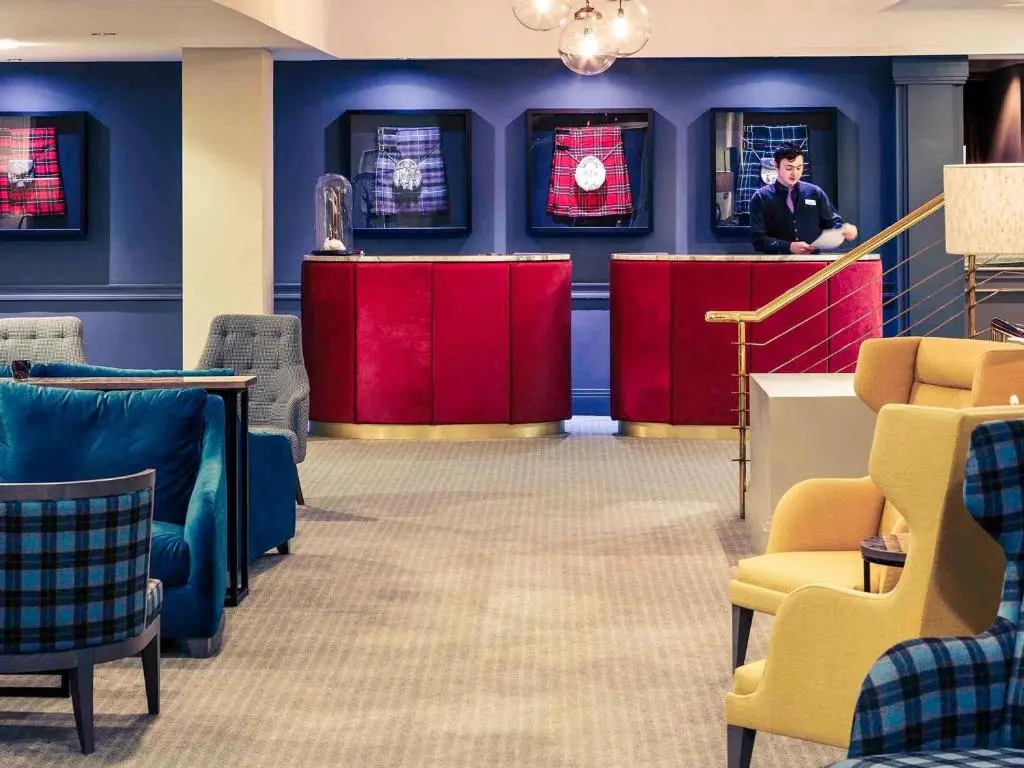 a man standing at a counter in a waiting room at Mercure Inverness Hotel in Inverness