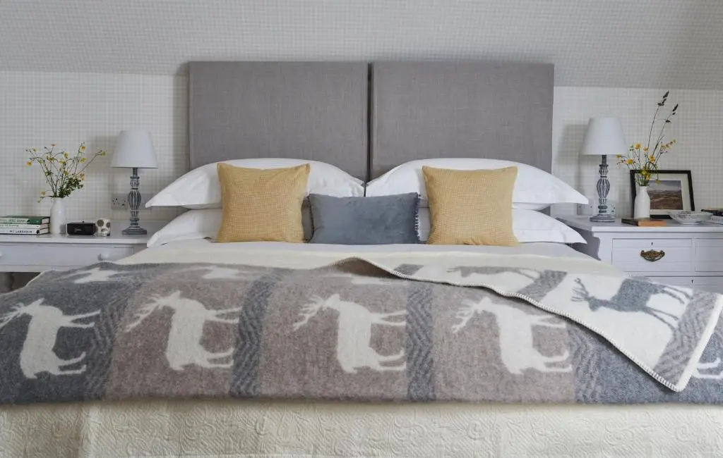 a bedroom with a bed with a horse blanket and pillows at Achnahatnich House in Aviemore