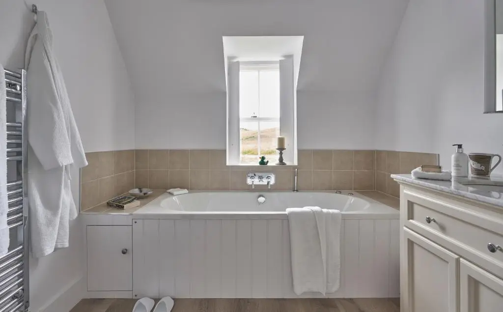a white bathroom with a tub and a window at Achnahatnich House in Aviemore