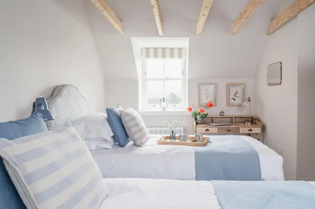a bedroom with two beds and a chair at Gleann Cottage - Seasgair Lodges in Kincraig