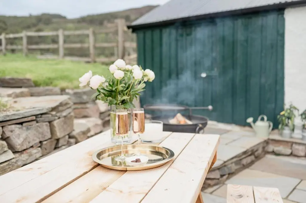 a table with a vase of white flowers on it at Gleann Cottage - Seasgair Lodges in Kincraig