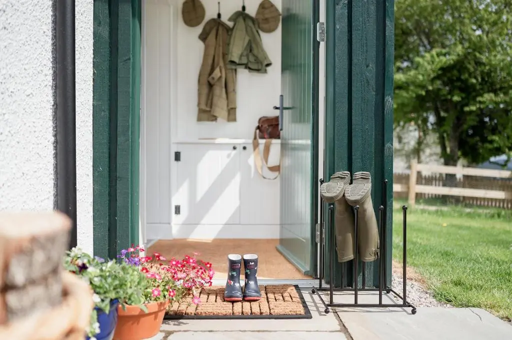 a pair of boots on a porch with flowers at Gleann Cottage - Seasgair Lodges in Kincraig