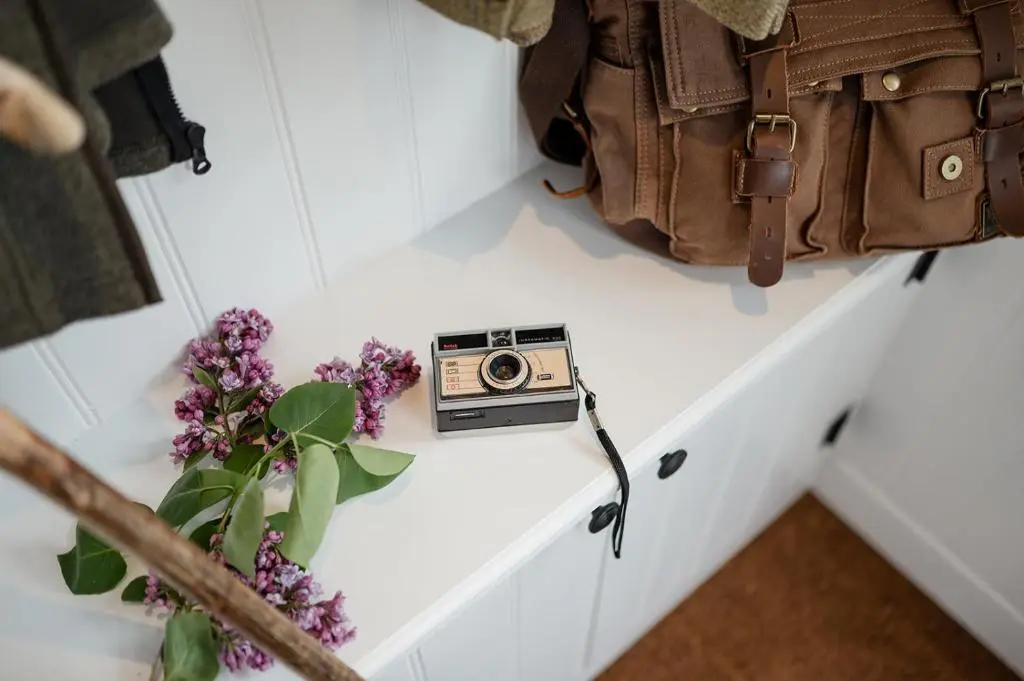 a camera on a table next to a bag and flowers at Beinn Cottage - Seasgair Lodges in Kincraig