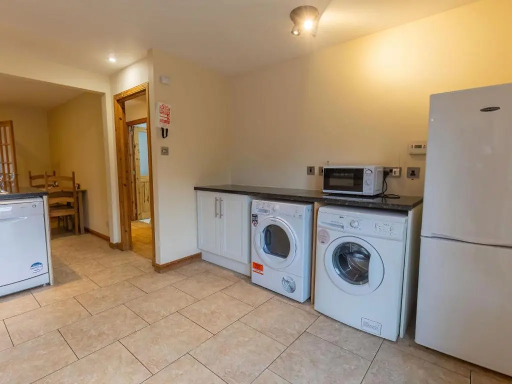 a kitchen with a washer and dryer and a refrigerator at Holiday Home Ardness Place by Interhome in Inverness