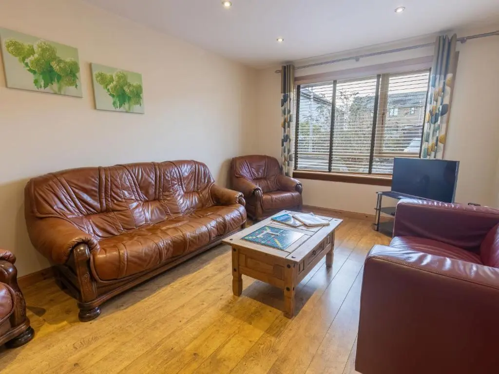 a living room with leather couches and a coffee table at Holiday Home Ardness Place by Interhome in Inverness
