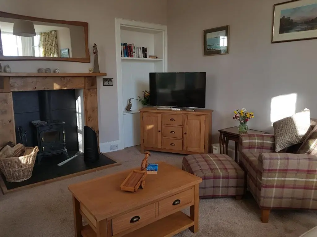 a living room with a fireplace and a television at Dalvey East Lodge in Forres