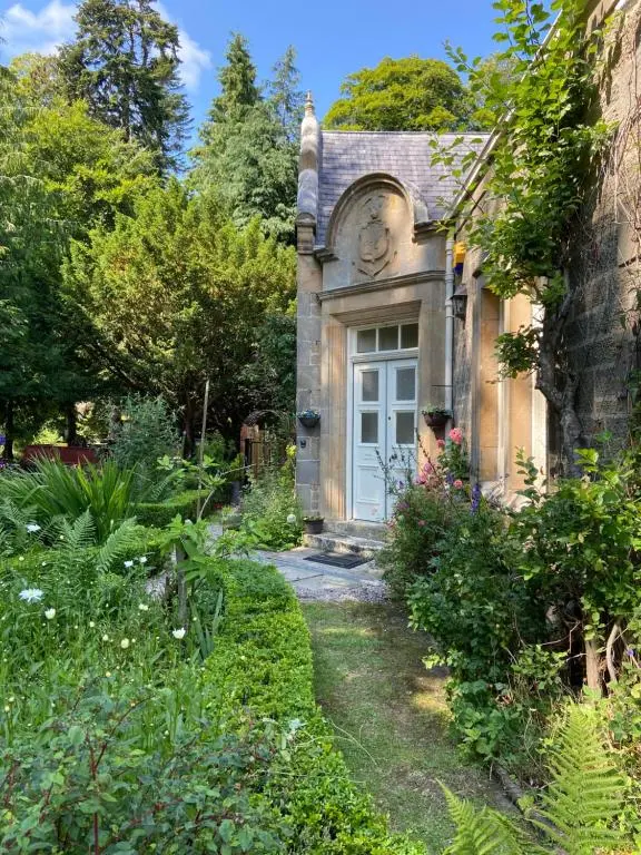 an old house with a white door in a garden at Dalvey East Lodge in Forres
