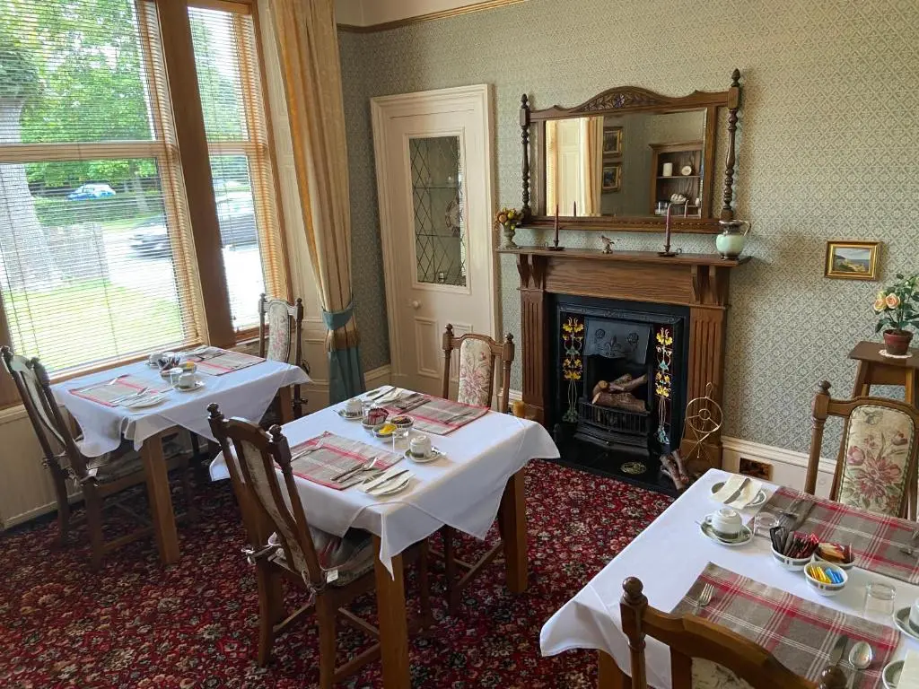a dining room with two tables and a fireplace at Corunna Bed & Breakfast and Corunna Cottage in Inverness