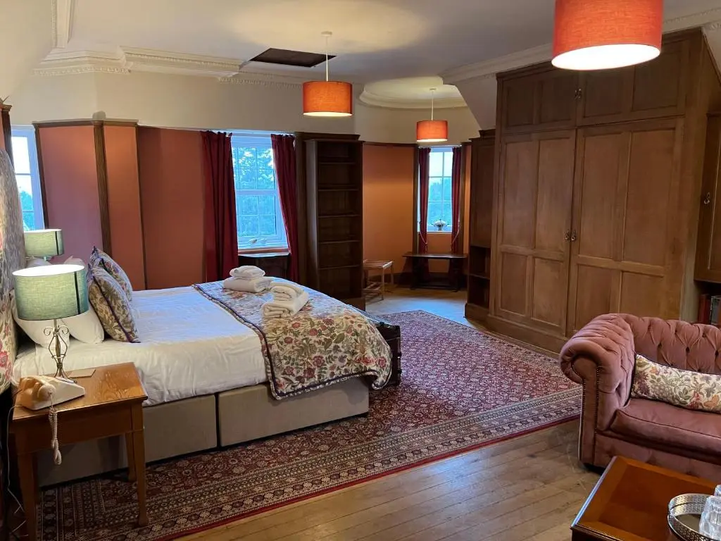 a bedroom with a bed and a couch and a chair at Dalmunzie Castle Hotel in Glenshee