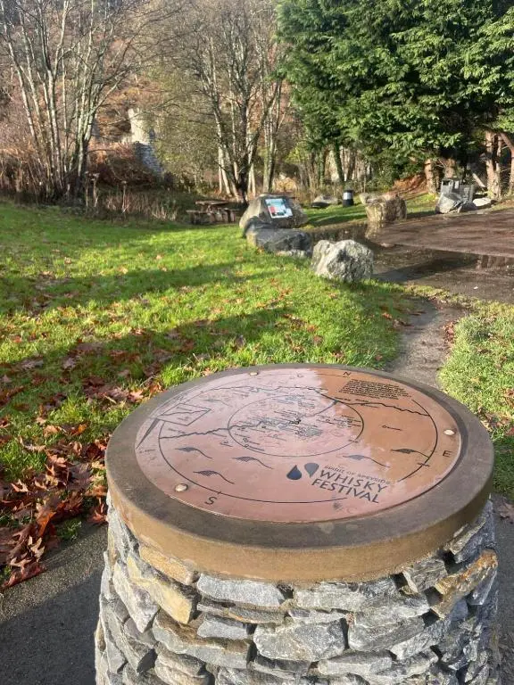 a stone wall with a clock in a park at Aberlour Apartment 92 B in Aberlour