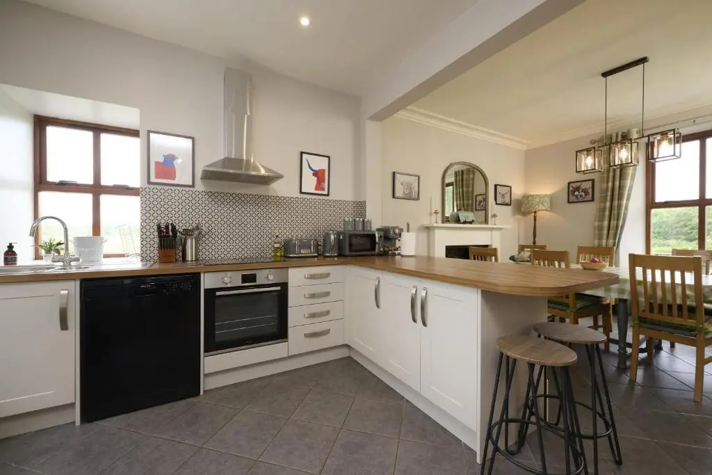 a kitchen with white cabinets and a wooden counter top at Dunaincroy Farmhouse in Inverness